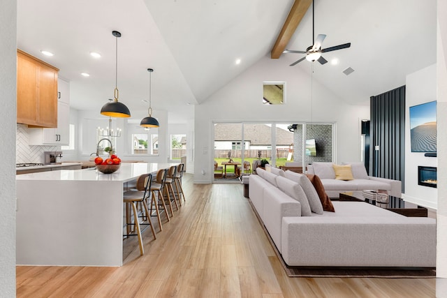 living room with light wood-style floors, high vaulted ceiling, beamed ceiling, and a fireplace