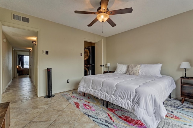 bedroom featuring visible vents, stacked washer and dryer, baseboards, and ceiling fan