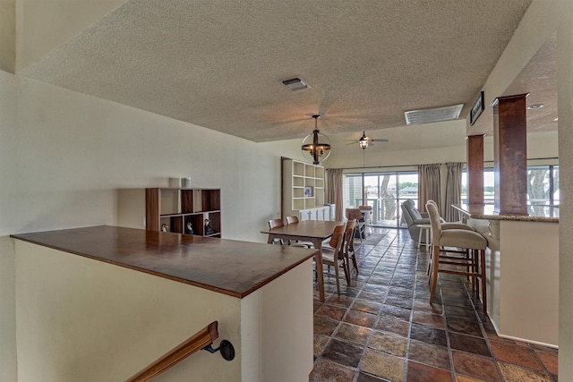 dining space featuring visible vents, a textured ceiling, and stone tile flooring