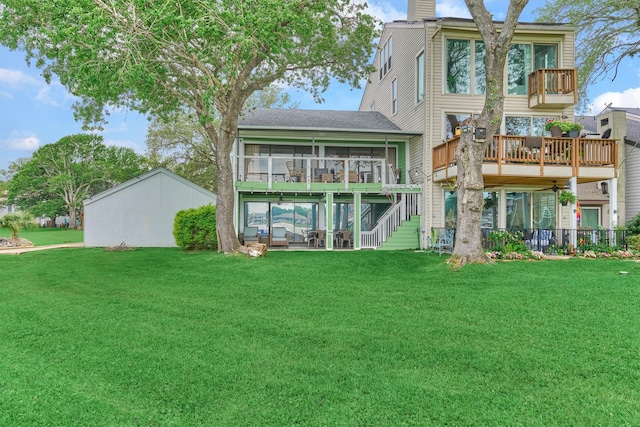 rear view of property with a shingled roof, a sunroom, a deck, stairway, and a lawn