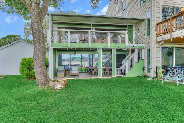 back of property featuring a balcony, a patio area, a yard, and stairway