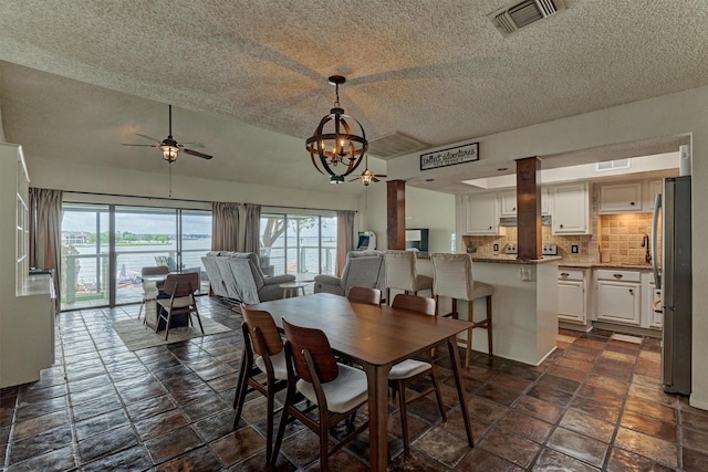 dining room featuring a wealth of natural light, ceiling fan with notable chandelier, a textured ceiling, and visible vents