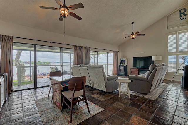 living room with stone tile flooring, a textured ceiling, ceiling fan, and high vaulted ceiling