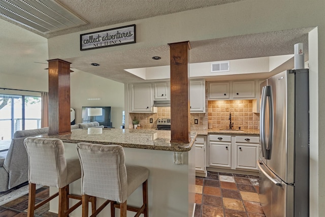 kitchen featuring light stone countertops, stainless steel appliances, open floor plan, and visible vents