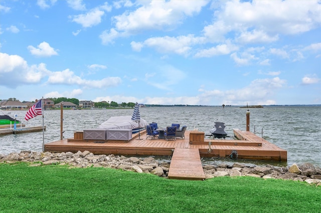 dock area with a lawn and a water view