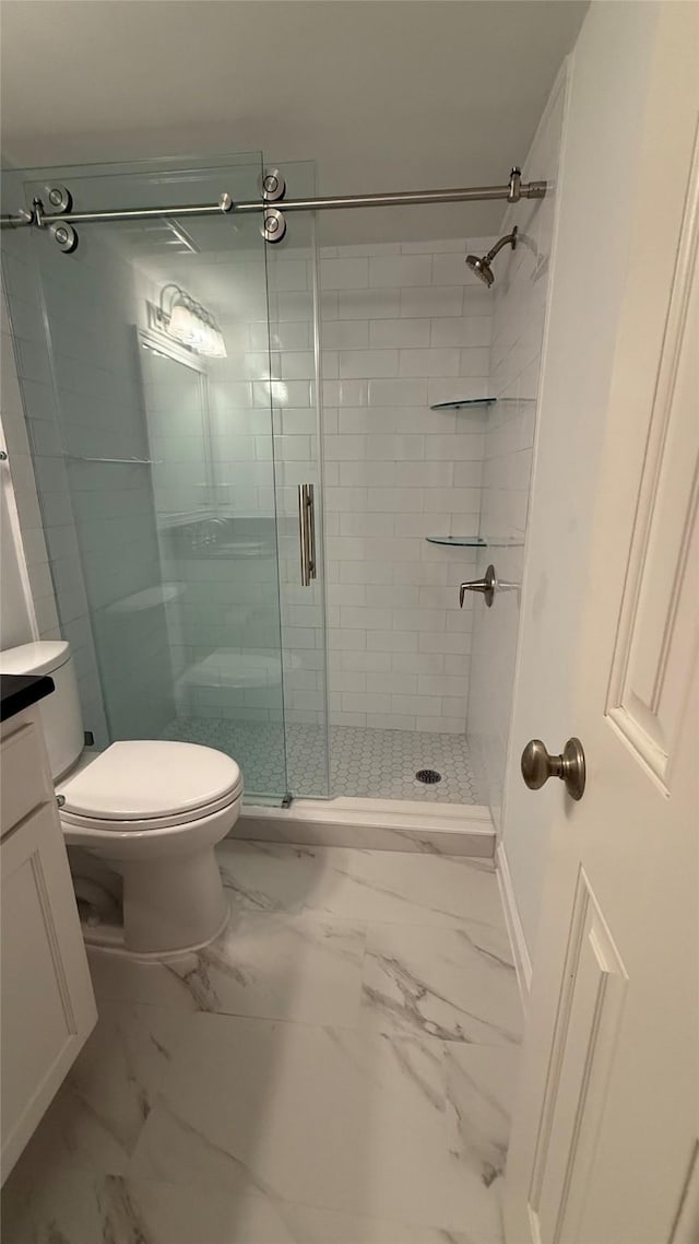 bathroom featuring a stall shower, baseboards, marble finish floor, toilet, and vanity
