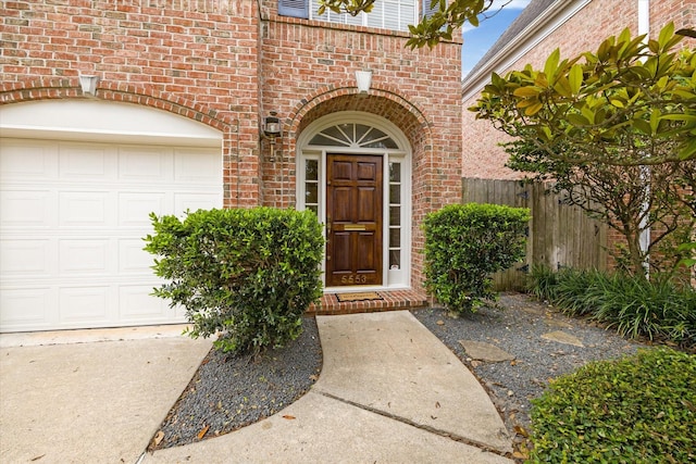 property entrance with brick siding, fence, and a garage