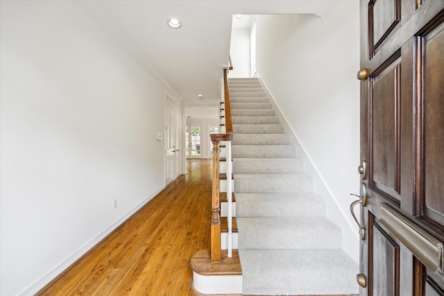staircase featuring crown molding, wood finished floors, baseboards, and recessed lighting