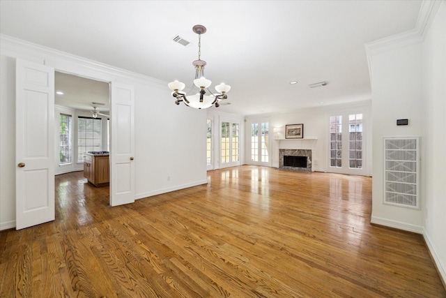 unfurnished living room with a healthy amount of sunlight, a chandelier, visible vents, and wood finished floors