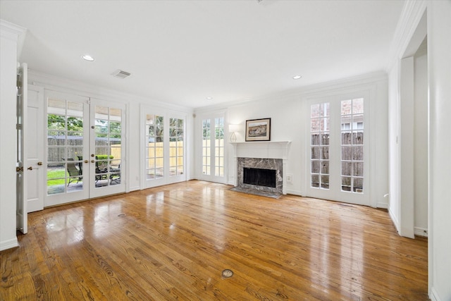 unfurnished living room featuring wood finished floors, french doors, a premium fireplace, visible vents, and ornamental molding