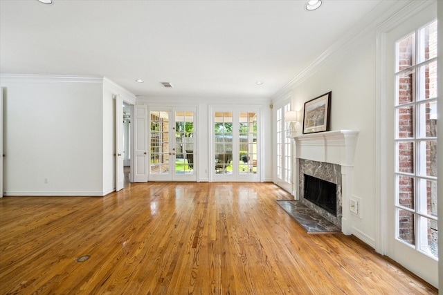 unfurnished living room with wood finished floors, visible vents, a high end fireplace, ornamental molding, and recessed lighting