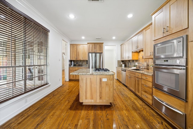 kitchen featuring a sink, a warming drawer, appliances with stainless steel finishes, decorative backsplash, and ornamental molding