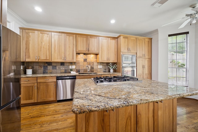 kitchen featuring a ceiling fan, crown molding, light wood-type flooring, backsplash, and appliances with stainless steel finishes