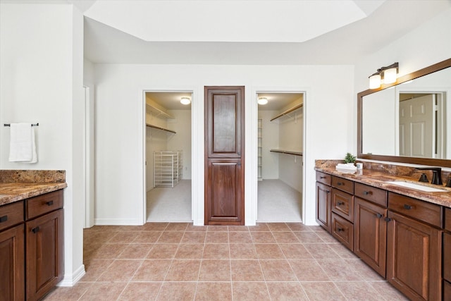 bathroom with baseboards, tile patterned flooring, vanity, and a spacious closet