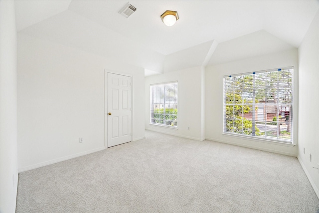 carpeted spare room featuring vaulted ceiling, baseboards, and visible vents