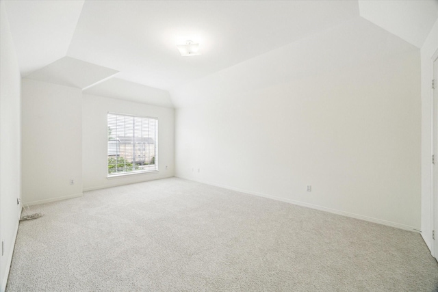 spare room with lofted ceiling, baseboards, and carpet