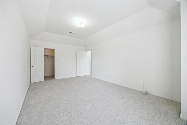 unfurnished bedroom with vaulted ceiling, light carpet, baseboards, and visible vents