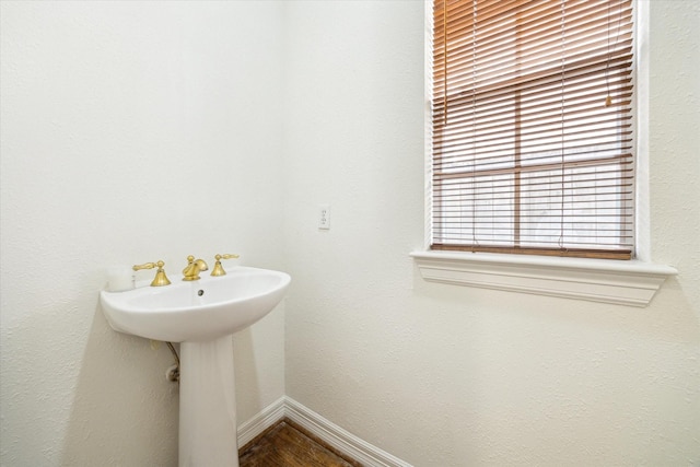 bathroom featuring wood finished floors, baseboards, and a sink