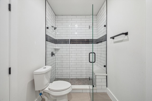 full bath featuring toilet, baseboards, and a shower stall
