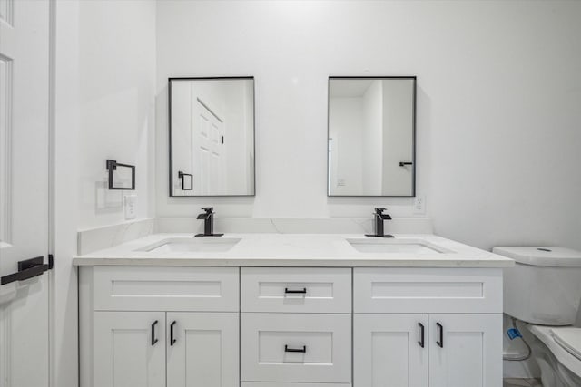 bathroom with double vanity, a sink, and toilet