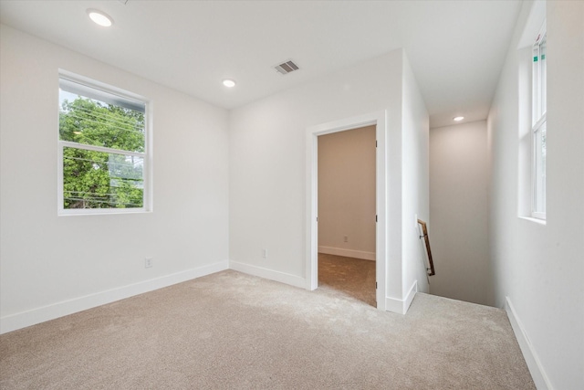 empty room featuring baseboards, light carpet, recessed lighting, and visible vents