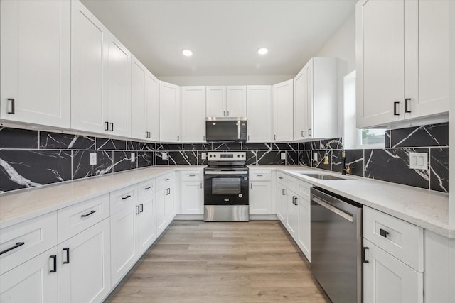 kitchen featuring decorative backsplash, appliances with stainless steel finishes, light stone countertops, a sink, and white cabinets