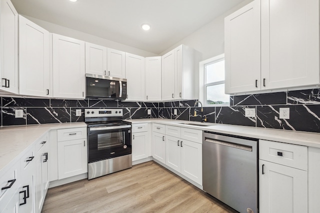 kitchen featuring appliances with stainless steel finishes, tasteful backsplash, a sink, recessed lighting, and white cabinetry