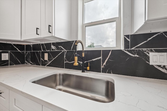 details with a sink, light stone countertops, backsplash, and white cabinetry