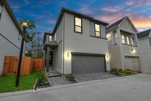 view of front facade featuring stucco siding, a garage, fence, and driveway