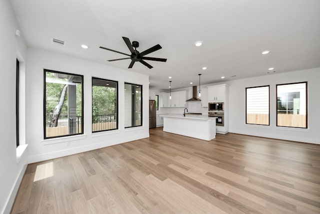 unfurnished living room featuring ceiling fan, light wood-style flooring, recessed lighting, baseboards, and visible vents
