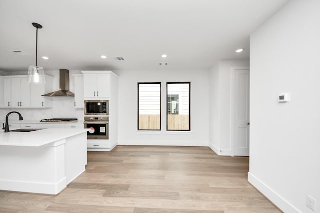 kitchen featuring visible vents, oven, wall chimney exhaust hood, built in microwave, and a sink