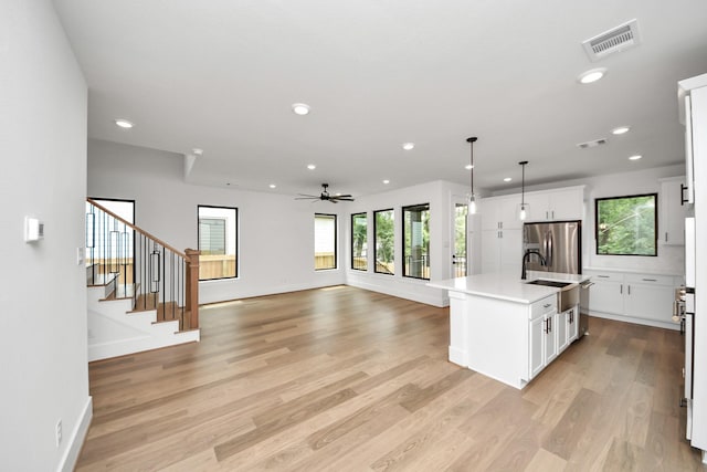 kitchen with visible vents, ceiling fan, stainless steel refrigerator with ice dispenser, light countertops, and light wood-style flooring