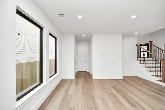 empty room with visible vents, stairs, light wood-style floors, baseboards, and recessed lighting