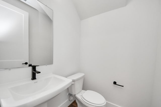 half bathroom featuring a sink, baseboards, and toilet