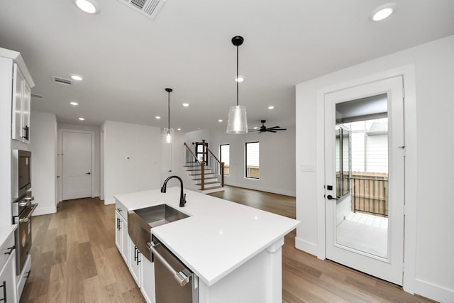 kitchen with light countertops, appliances with stainless steel finishes, a sink, and light wood-style flooring