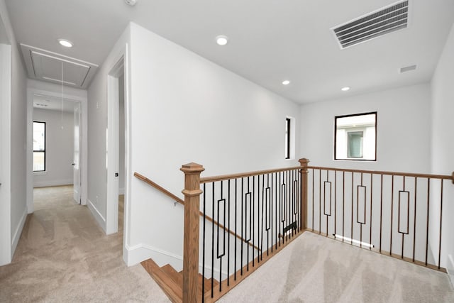 hallway featuring carpet flooring, attic access, baseboards, an upstairs landing, and visible vents