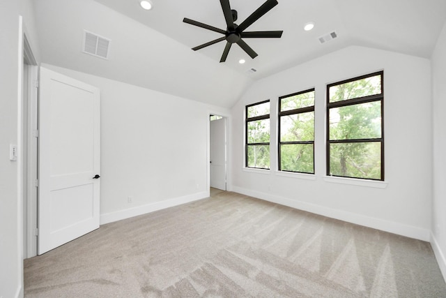 unfurnished bedroom with baseboards, vaulted ceiling, light colored carpet, and visible vents