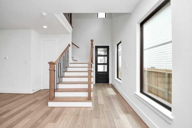entrance foyer with recessed lighting, baseboards, light wood-style flooring, and stairway
