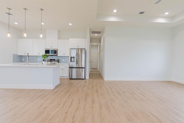 4206 Mason Dr, Galveston, TX 77554 - kitchen featuring appliances with stainless steel finishes, light wood finished floors, light countertops, white cabinetry, and decorative backsplash