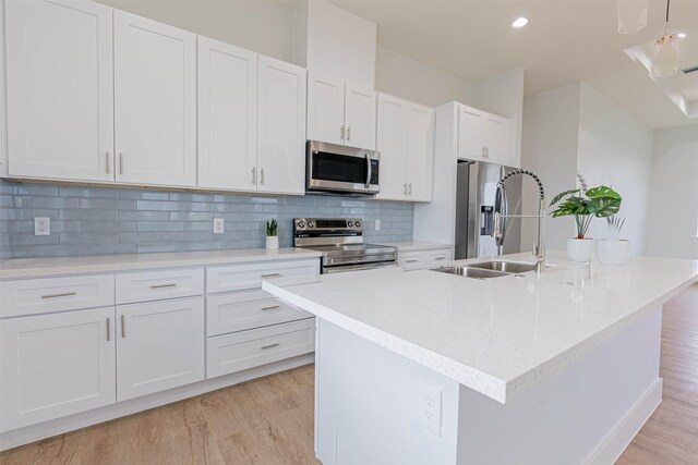 4206 Mason Dr, Galveston, TX 77554 - kitchen featuring light wood-style floors, a center island with sink, white cabinets, a sink, and appliances with stainless steel finishes
