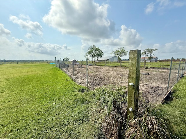 surrounding community with a lawn, a rural view, and fence