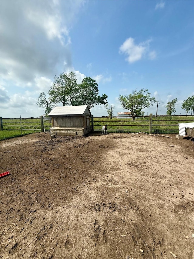 view of yard featuring a rural view, fence, and an outbuilding