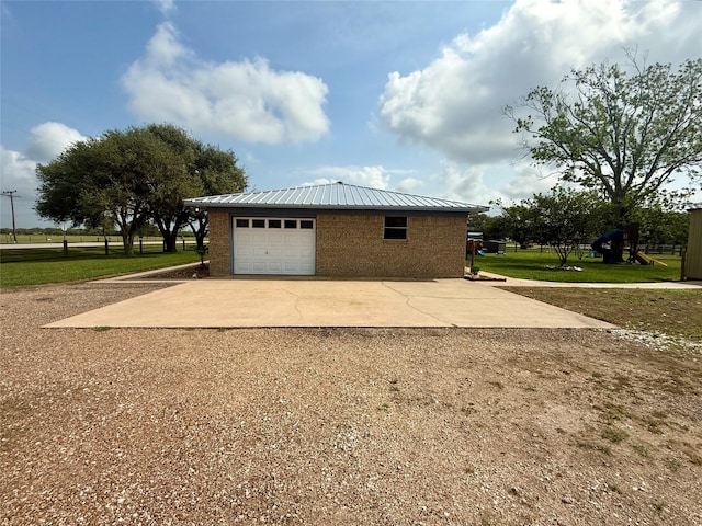 view of home's exterior with an attached garage, brick siding, concrete driveway, an outdoor structure, and metal roof