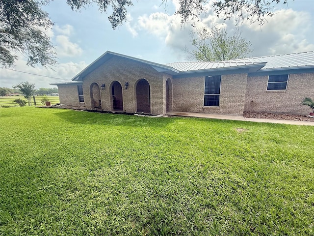 single story home with brick siding, metal roof, and a front yard