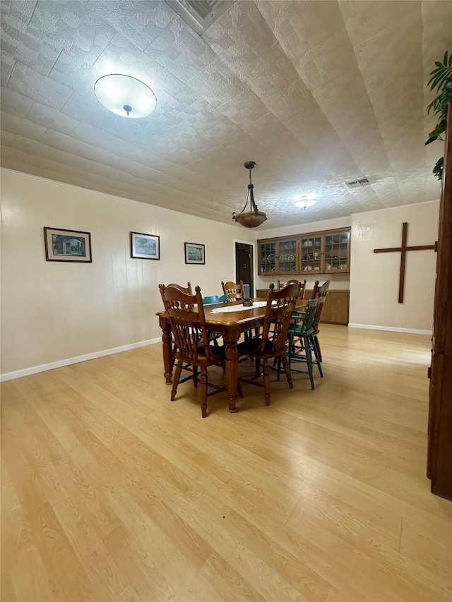 dining space featuring baseboards, visible vents, and light wood finished floors