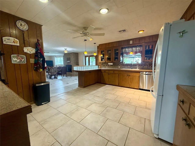 kitchen featuring stainless steel dishwasher, freestanding refrigerator, a peninsula, open floor plan, and a sink