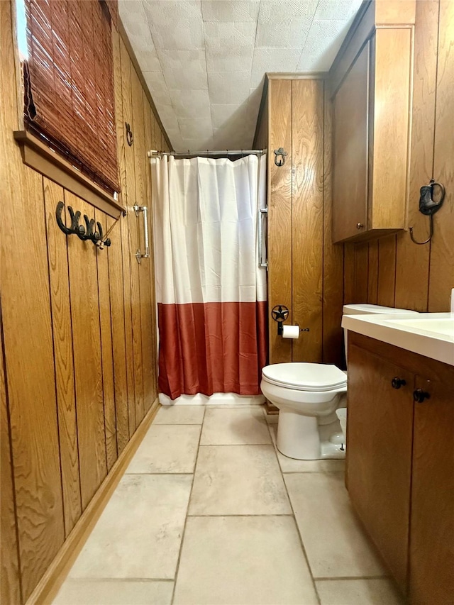 full bathroom with a shower with curtain, tile patterned flooring, wood walls, vanity, and toilet