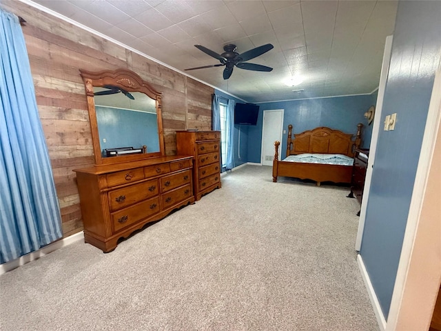 carpeted bedroom with wooden walls, baseboards, crown molding, and ceiling fan