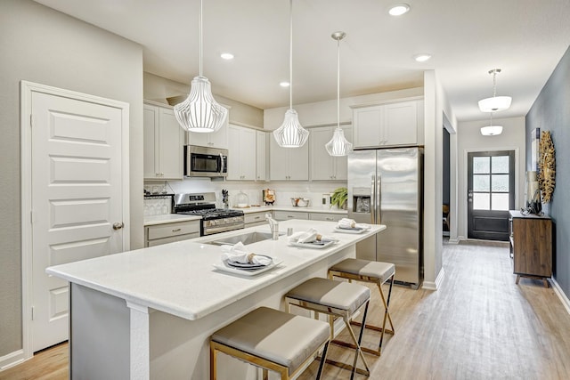 759 Red Mulberry St, La Marque, TX 77568 - kitchen with a breakfast bar, light wood-type flooring, light countertops, a sink, and appliances with stainless steel finishes