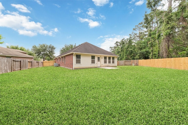 rear view of property with brick siding, a fenced backyard, a patio area, and a yard